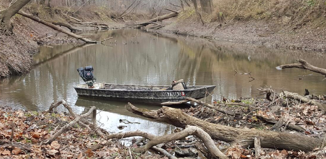 mudmotor on a small mudboat on a small river with fallen trees and branches